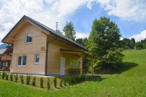 une maison en bois dans un champ verdoyant avec des arbres dans l'établissement Dijkstra`s Cottage 679, à Kötschach-Mauthen