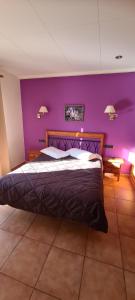 a bedroom with a large bed with purple walls at Hostal Mont-Rock in Montagut