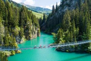 a group of people riding bikes across a bridge over a river at Superbe appartement en résidence avec piscine. in Albertville +13 photos