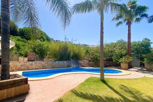 a swimming pool in a yard with palm trees at Bed & Breakfast Casa del Palta in Canillas de Albaida