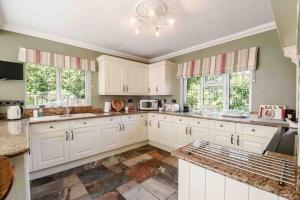 a large kitchen with white cabinets and windows at Mireystock Indoor Pool, Games Bar, Spa Steam Cabin in Lydbrook