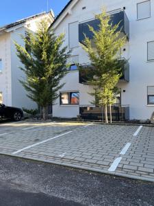 two trees in a parking lot in front of a building at Ferienwohnung Gergert Nr.2 in Löwenstein