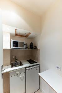Studio sur les Quais de Seine في باريس: مطبخ صغير مع دواليب بيضاء ومغسلة