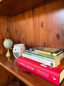 une pile de livres sur une étagère dans l'établissement Nanna's Way, Wellness Retreat, à Victoria