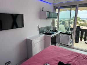 um quarto com uma cozinha com um lavatório e uma televisão em VILLAGE NATURISTE em Cap d'Agde