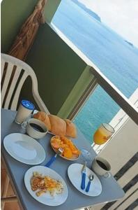 a table with plates of breakfast food on it at Apartamento pé na areia com vista para o mar aberto in Guarujá
