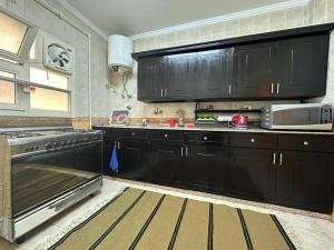 een keuken met zwarte kasten en een magnetron bij Luxurious apartment for rent with Nile view for families only in Caïro