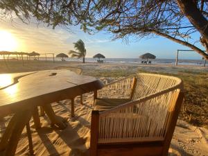 a wooden table and chairs on a beach with umbrellas at Mar Azul - Playa y Turismo in Camarones