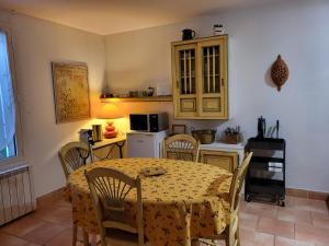 a dining room with a table and chairs and a kitchen at La Chouette de Camargue in Aigues-Mortes