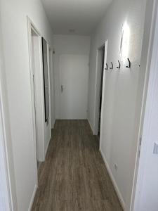 pusty korytarz z białymi ścianami i drewnianą podłogą w obiekcie ButschisBude w mieście Sierksdorf
