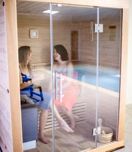 two women in a sauna with a swimming pool at Domaine des Bois Argentés in Saugirard