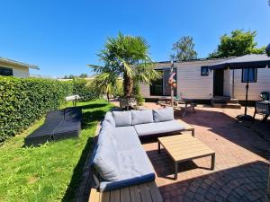 a couch and a table on a patio at De Corner van Zeeland met jacuzzi in Sint Annaland