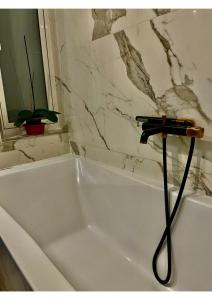 a white bath tub with a black hose at Airport Accommodation Bedroom with Bathroom Self Check In and Self Check Out Air-condition Included in Mqabba