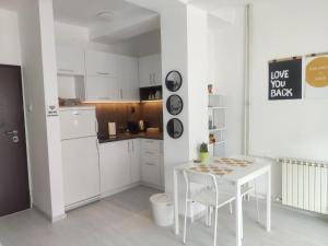a white kitchen with a white table and chairs at City Center White Apartment! in Skopje