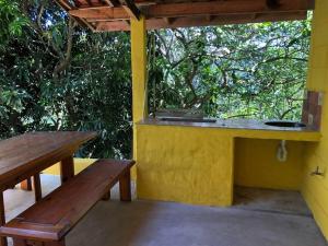 a yellow building with a table and benches on a porch at Casa Tupa Recanto Familiar Pague 2 Minimo e fique 3 menos feriados in Natividade da Serra