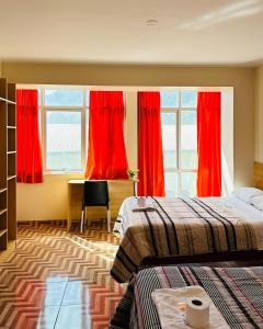 Cette chambre comprend deux lits et un bureau avec des rideaux rouges. dans l'établissement LA CASONA DE YANAHUANCA, à Yanahuanca