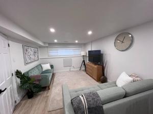 een woonkamer met een bank en een klok aan de muur bij Long Stay Luxury New Spacious Apartment - Sleeps 6 in Kitchener