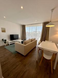uma sala de estar com um sofá, uma televisão e uma mesa em Praia da Rocha Torre Verde - Portimao em Portimão