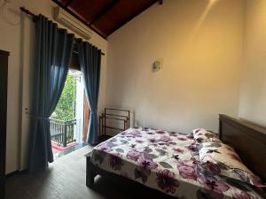 a bedroom with a bed with a floral bedspread and a window at Sagya Residencies in Panadura
