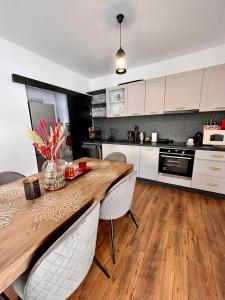 cocina con mesa de madera y armarios blancos en Kenzo Chalet, en Porumbacu de Sus