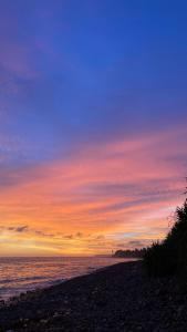 einen Sonnenuntergang am Strand mit Himmel und Wasser in der Unterkunft V & E Home Stay Cimaja Beach in Cimaja