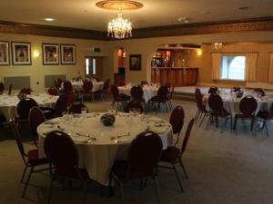 un salón de banquetes con mesas y sillas blancas en The Begelly Arms Hotel en Kilgetty