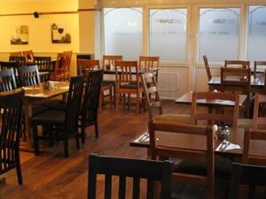 KilgettyにあるThe Begelly Arms Hotelの木製のテーブルと椅子、窓のあるレストラン