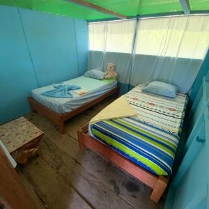 Habitación pequeña con 2 camas y un osito de peluche en Refugio Rural Amazonas, en Iquitos