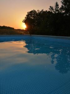 una piscina con puesta de sol en el fondo en Cocooning au Saut du Loup en Lavergne