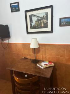 a table with a lamp and a picture on the wall at Casa de la Mancha in Mota del Cuervo