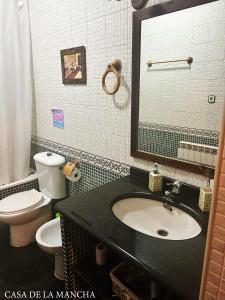 a bathroom with a sink and a toilet and a mirror at Casa rural compartida Casa de la Mancha in Mota del Cuervo +17 photos