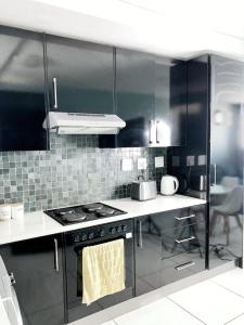 uma cozinha com armários pretos e um forno com placa de fogão em Cosy Apartment In The Heat Of The City em Windhoek