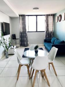 a living room with a table and white chairs at Cosy Apartment In The Heat Of The City in Windhoek
