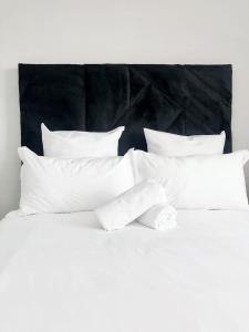 a pile of white pillows on a white bed at Cosy Apartment In The Heat Of The City in Windhoek