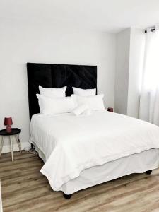 a bedroom with a large white bed with a black headboard at Cosy Apartment In The Heat Of The City in Windhoek