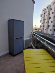 einen gelben Stuhl und einen Kühlschrank auf dem Balkon in der Unterkunft Appartement T2 Ensoleillé au Barcarès in Le Barcarès