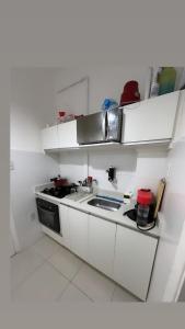 a white kitchen with a stove and a sink at house JV in Rio de Janeiro