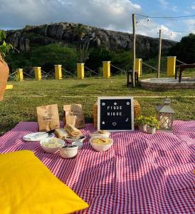 una mesa de picnic con comida y una señal en ella en Chalé Entre as Pedras en Serra de São Bento