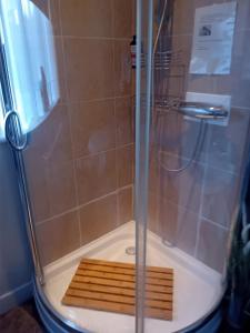 a shower with a glass door and a wooden floor at Falcon Towers in Stowmarket