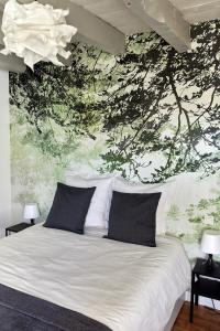 een slaapkamer met een wit bed en een muurschildering van bomen bij La Breizhidence in Combourg