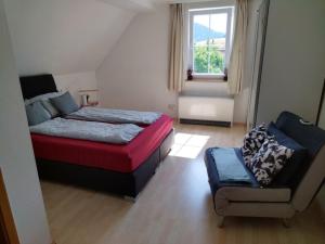 a bedroom with a bed and a chair and a window at Ferienwohnung Waldrausch in Baiersbronn