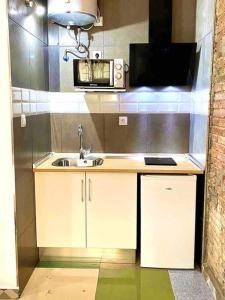 eine kleine Küche mit einer Spüle und einer Mikrowelle in der Unterkunft L1 Estudio nuevo! Al lado del metro en Sants in Barcelona