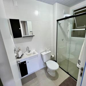 a white bathroom with a toilet and a shower at Apto na Praia de Fora - Palhoça in Palhoça