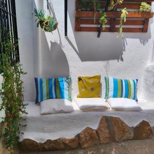 a white bench with pillows on a wall at la casita del pueblo PET friendly granada in Acebuches
