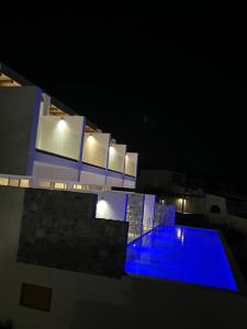 un edificio con piscina azul por la noche en Johannes Boutique Apartments & Suites, en Afantou