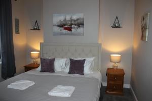 a bedroom with a white bed with two lamps and a painting at Ashville Grange in Scarborough