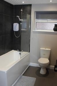 a bathroom with a tub and a toilet and a shower at Ashville Grange in Scarborough