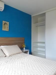 1 dormitorio con 1 cama con pared azul en Apart Itapua, en Salvador