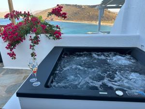a hot tub with a glass of wine and flowers at Panormos Village Hotel in Mykonos