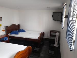 Habitación con 2 camas y TV en la pared. en HOTEL PARAISO DE LAS GEMELAS en Montenegro